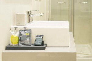 Un lavabo con espejo, grifo y dispensador de jabón.