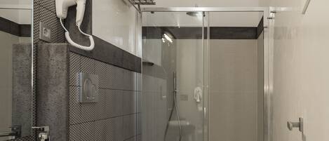Un baño moderno con un espejo grande, un lavabo, un inodoro y una ducha.