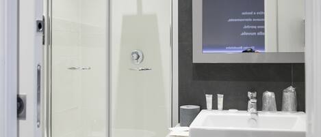Une salle de bain moderne avec une douche à parois de verre, un lavabo blanc et des articles de toilette disposés sur le comptoir.