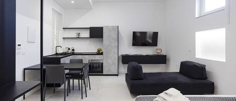 Una habitación moderna y minimalista con una cama, un sofá, un comedor y una cocina.