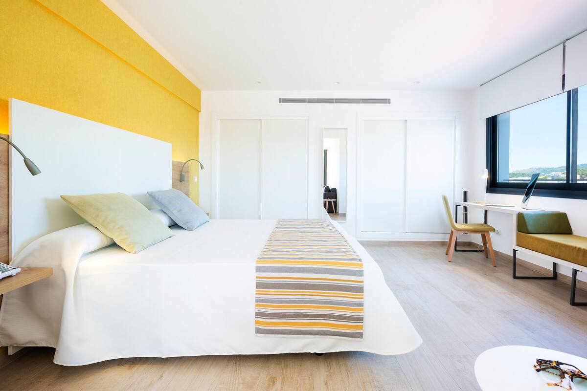 Een moderne hotelkamer met een groot bed, een bureau, een stoel en uitzicht op de stad.