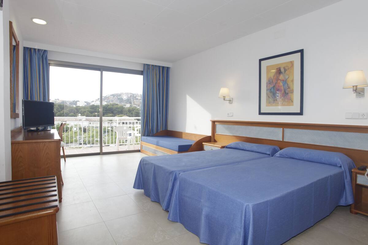 Een hotelkamer met twee bedden, een televisie, een bureau en een balkon met gordijnen.