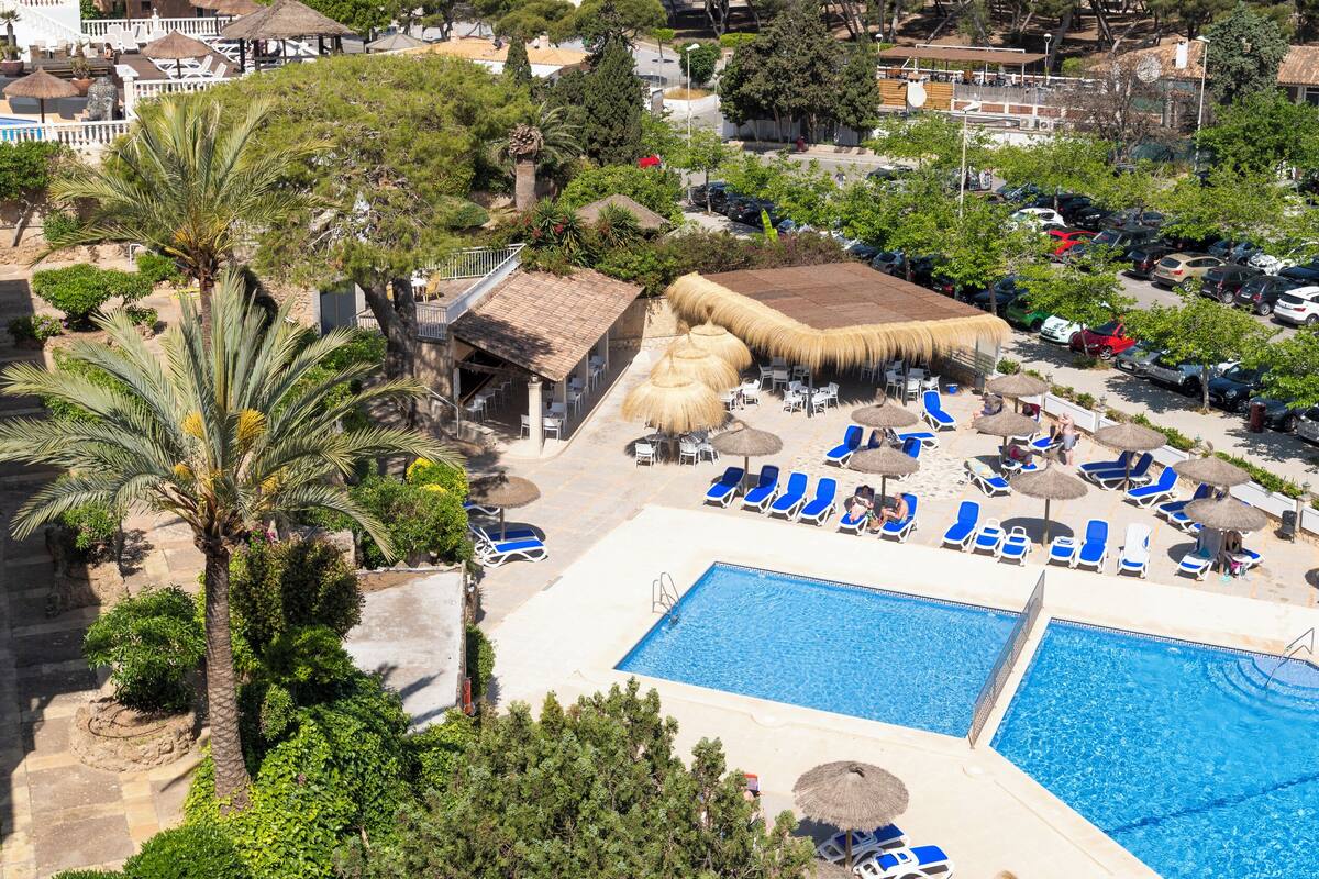 Een resort met een zwembad, ligbedden en uitzicht op zee.