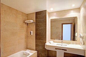 Un baño moderno con bañera, lavamanos y un espejo grande.