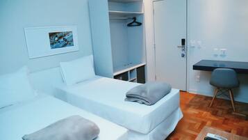 Una habitación con dos camas, un escritorio, un armario y un cuadro en la pared.