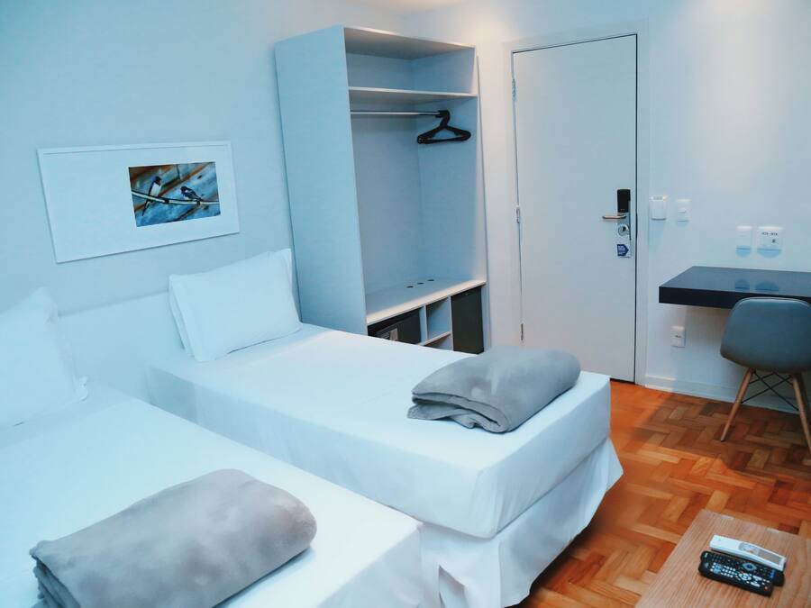 Una habitación con dos camas, un escritorio, un armario y un cuadro en la pared.