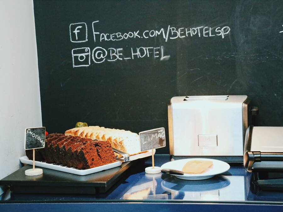 Presentació de postres amb una torta de xocolata i una torta blanca, una pissarra amb noms d'ús a les xarxes socials i una impressora sobre un taulell.