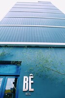 Un moderno edificio de hotel con fachada azul y un letrero que dice "BÉ HOTEL".