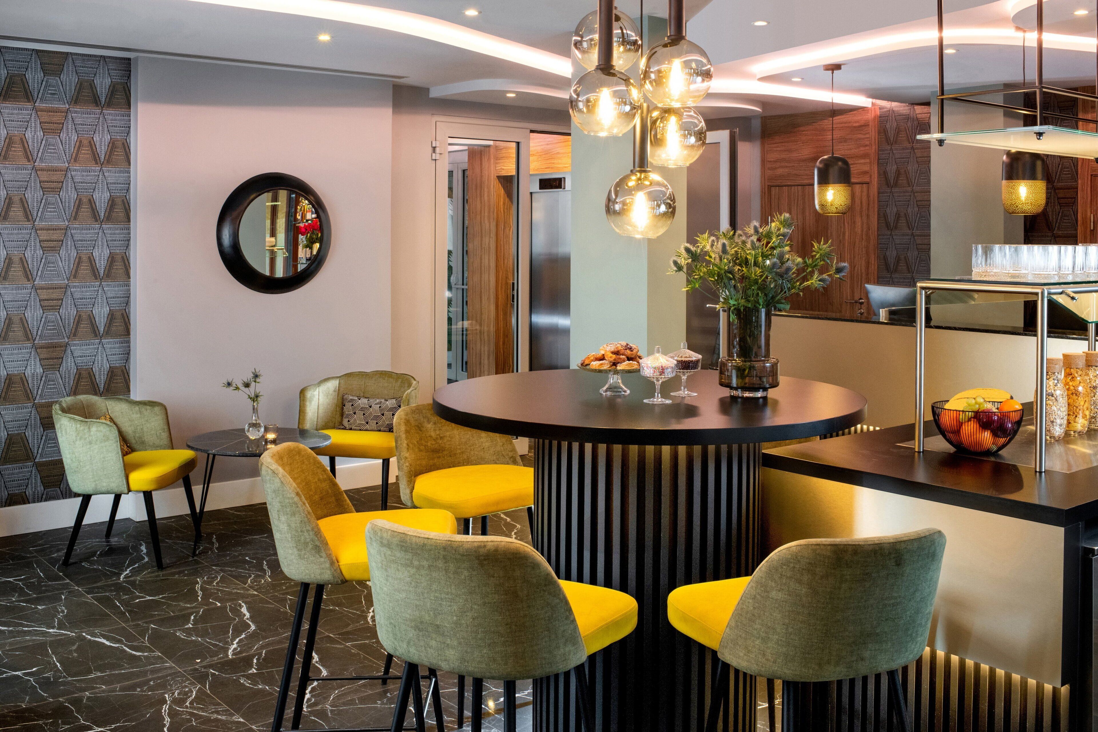 Un comedor moderno con una mesa redonda, sillas amarillas y un florero central.