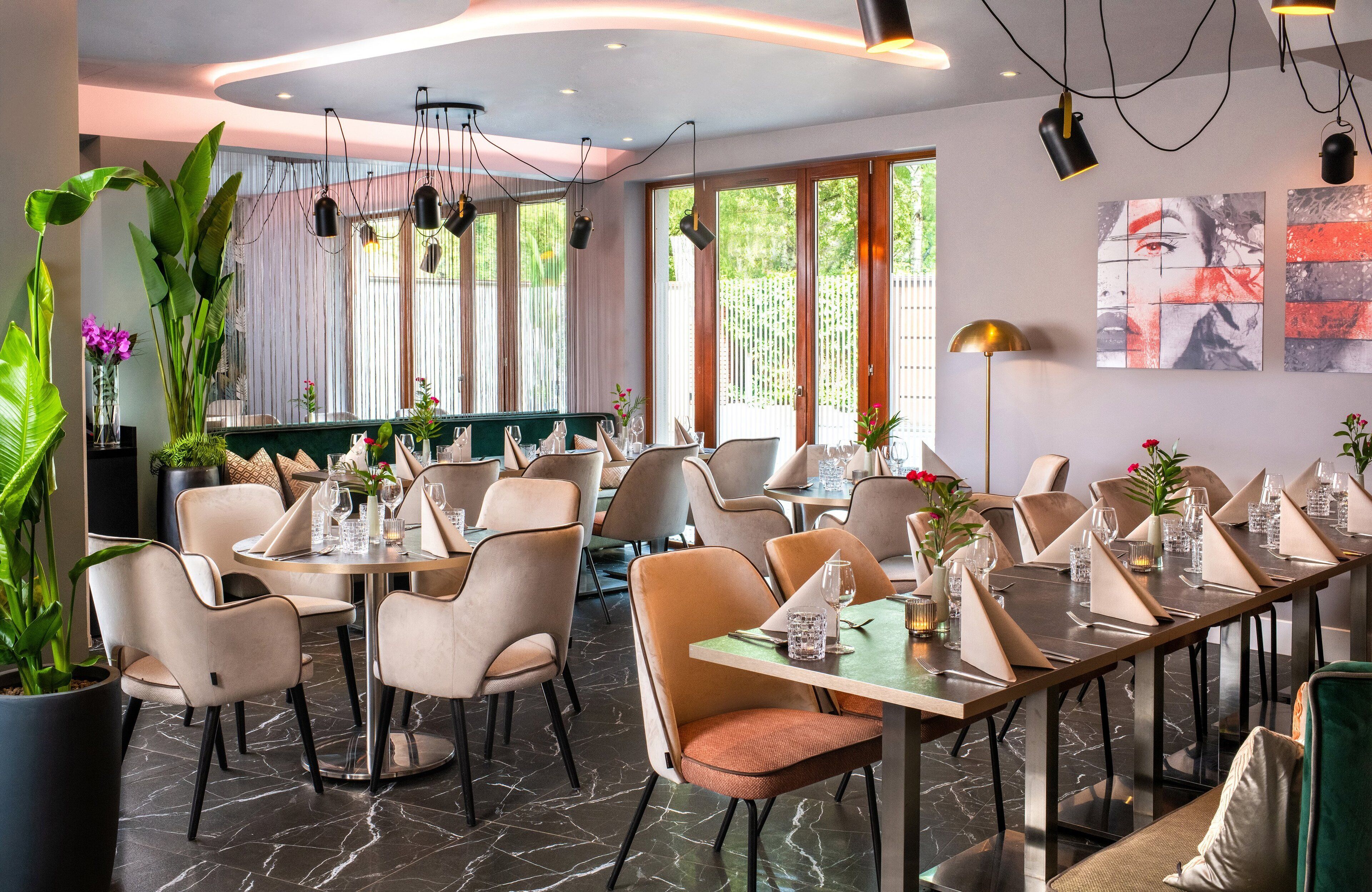 A restaurant with a long dining table, multiple chairs, and potted plants.