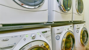 A row of stacked front-loading washing machines in a laundry room.