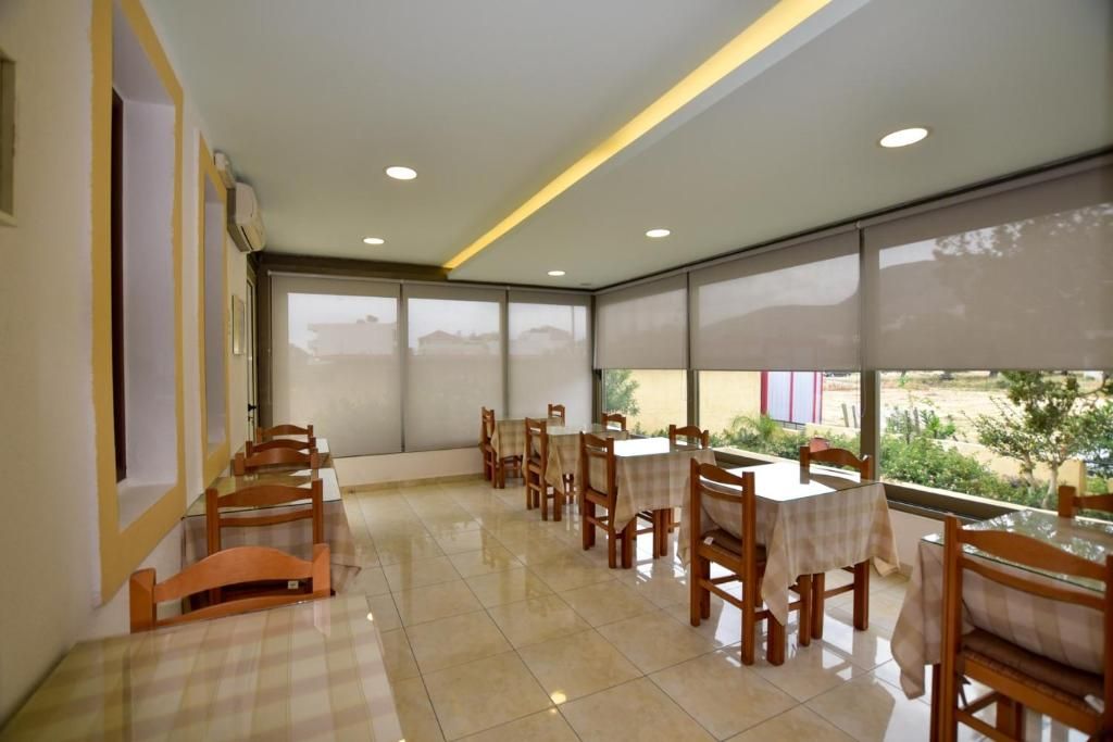 Un espace repas avec des tables et des chaises, de grandes fenêtres et un plafond doté d’un éclairage encastré.