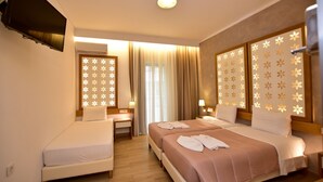 Een hotelkamer met twee bedden, een televisie, een raam met gordijnen en decoratieve lichtpanelen.