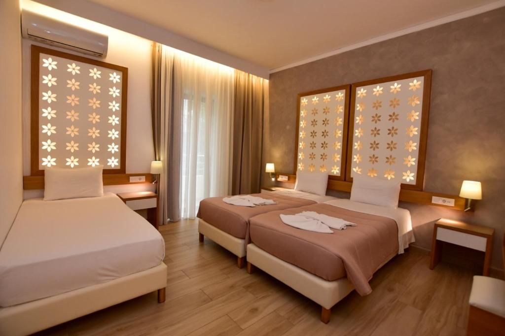 A hotel room with two beds, a sitting area, and a large window with curtains.