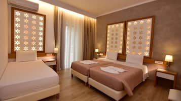 A hotel room with two beds, a sitting area, and a large window with curtains.