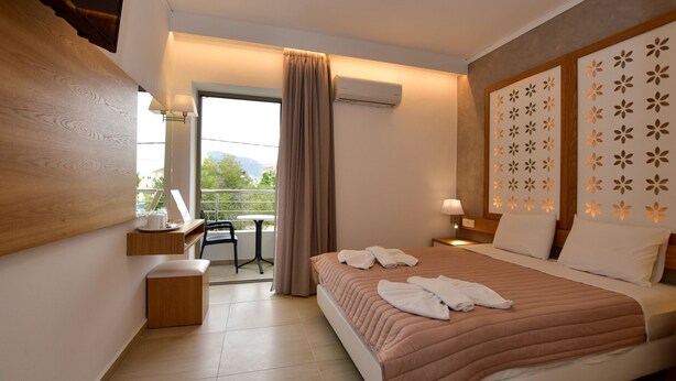 Een hotelkamer met een bed, een bureau, een stoel, een balkon en een airconditioning.
