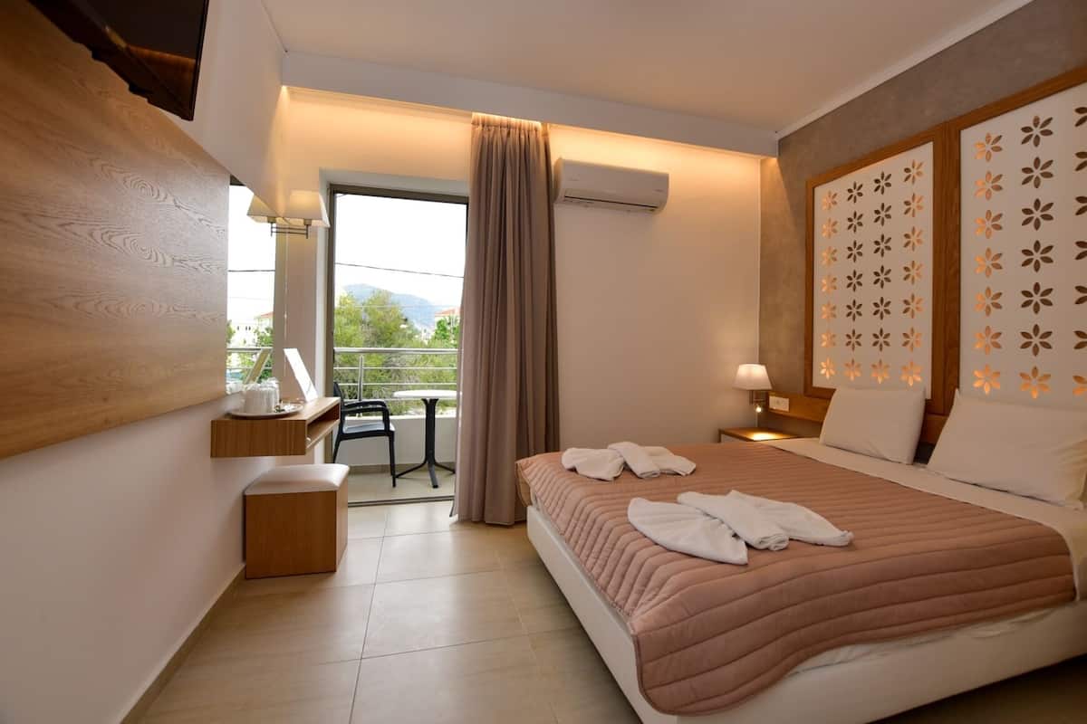 Een hotelkamer met een bed, een bureau, een stoel, een balkon en een airconditioning.