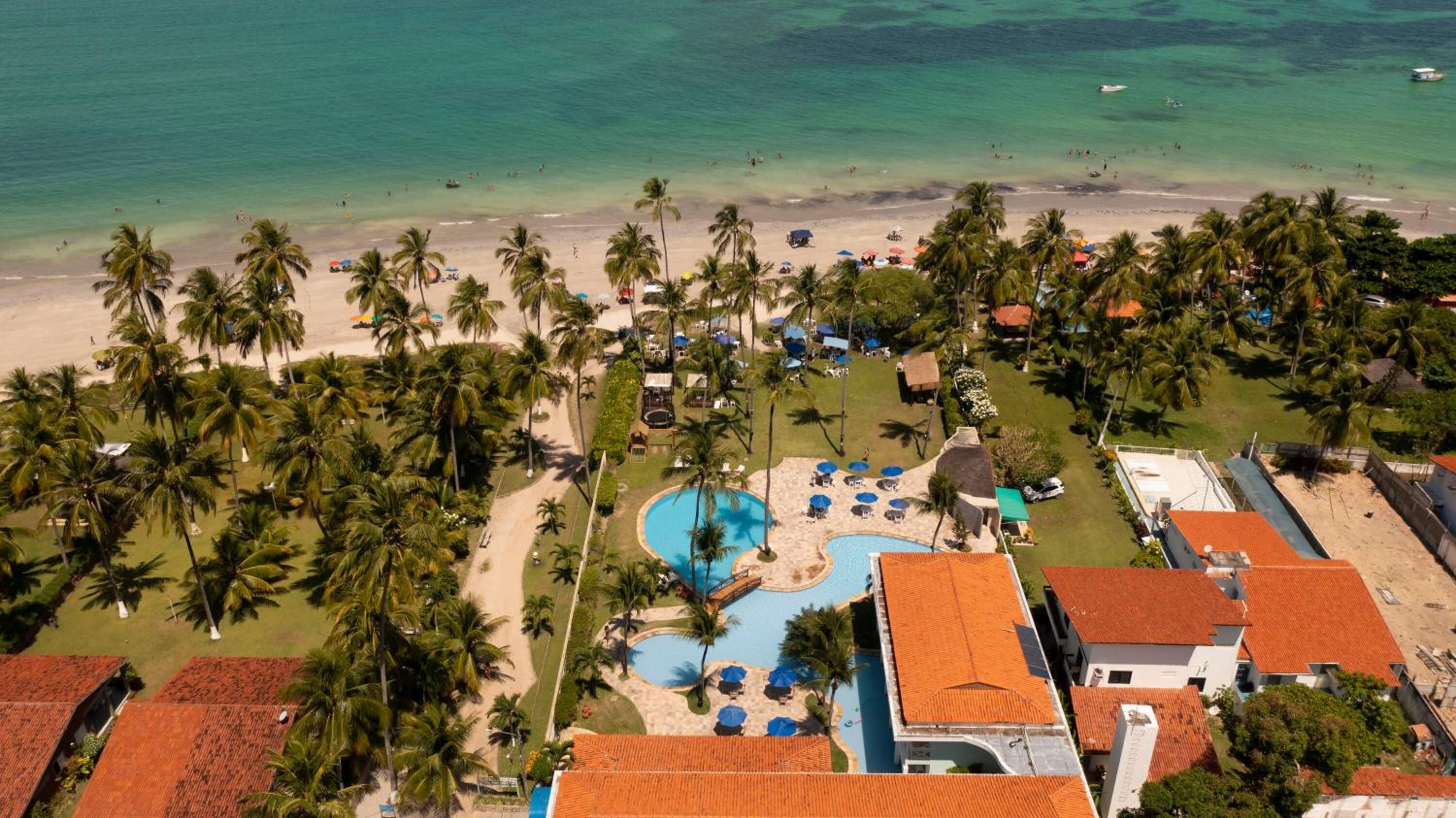 Um resort com piscina, praia e palmeiras.