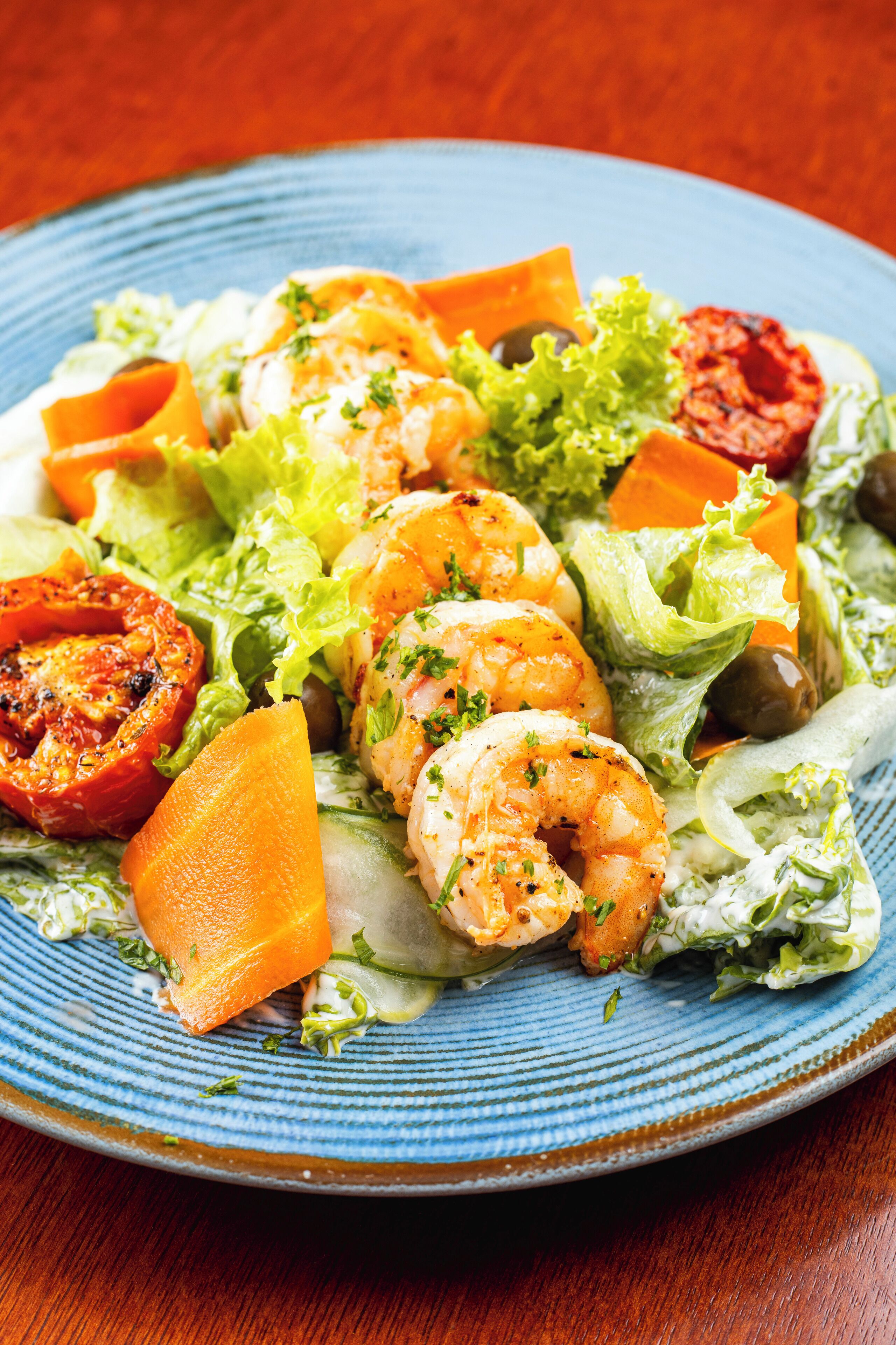 A plate of shrimp and vegetables on a blue plate.