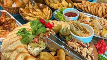 Una mesa de buffet con diferentes alimentos, incluyendo pan, papas fritas y salsas.