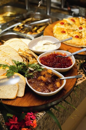 Un buffet proposant divers plats, notamment du pain, une pizza et des bols de sauces pour tremper.