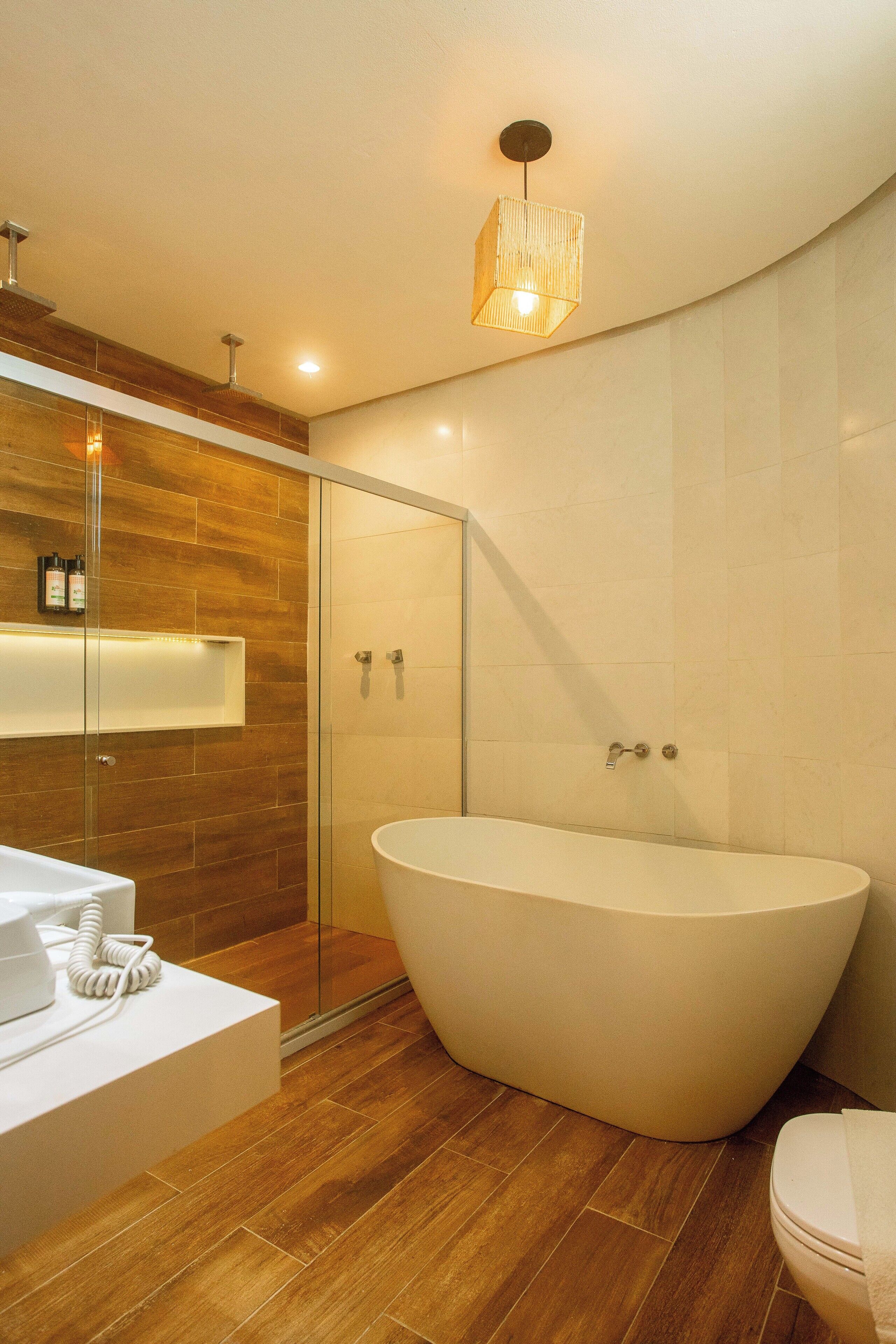 Une salle de bain moderne dotée d’une baignoire sur pieds, d’une douche à parois de verre et d’un meuble-lavabo avec un miroir et un plan de travail.