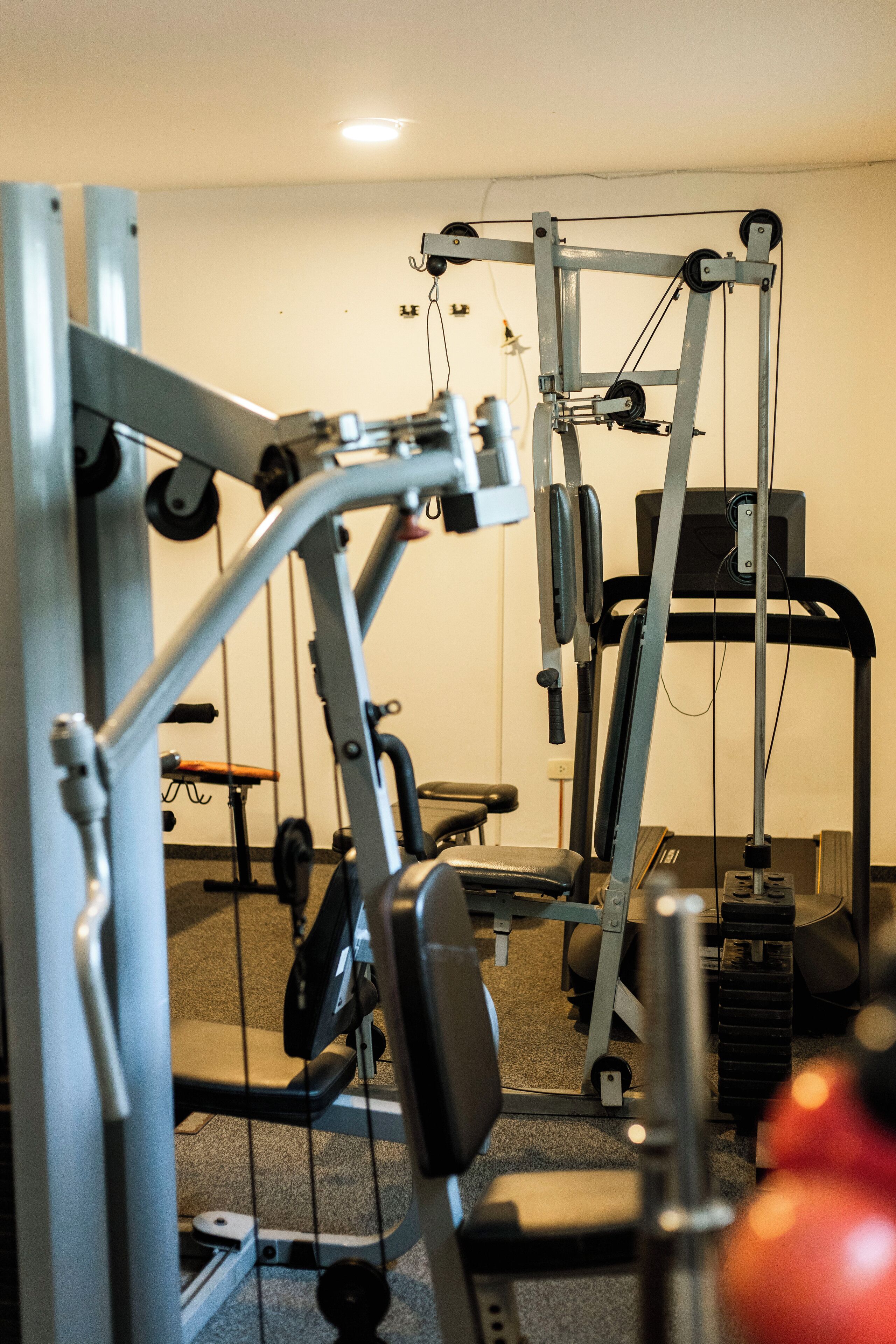 A gym with various exercise machines, including a treadmill and weightlifting equipment.