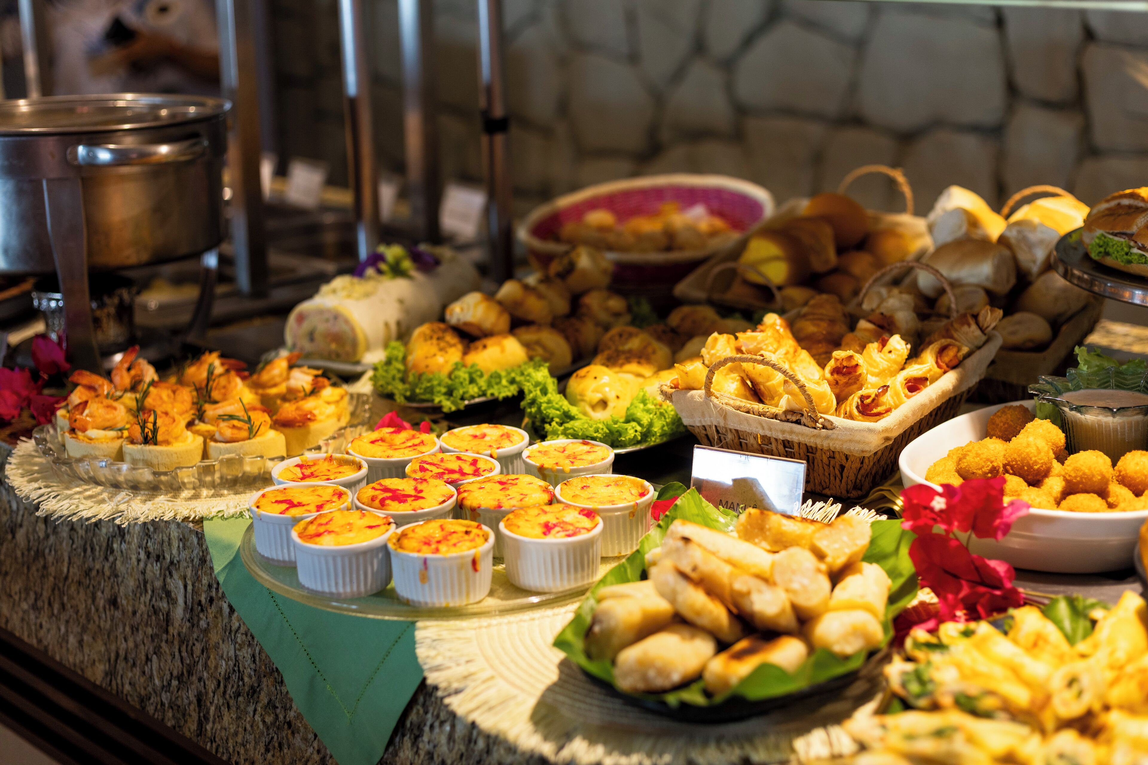 A buffet with various dishes including bread, pastries, and small bowls of food.