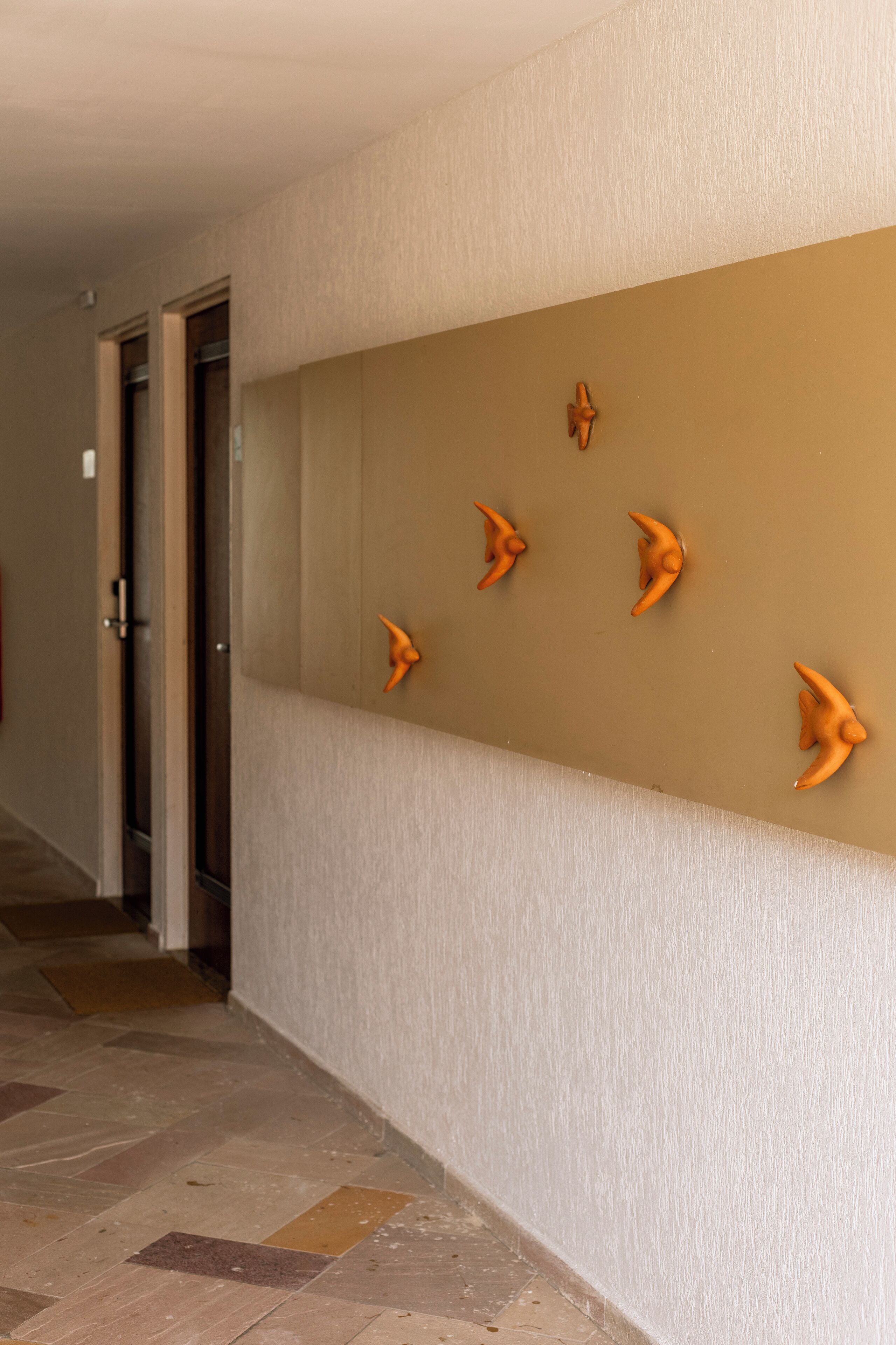 A hallway with a beige wall and a tiled floor.