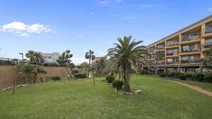A well-maintained lawn with palm trees, a pathway, and a multi-story building with balconies.