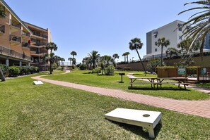 Un patio con césped, una mesa de picnic, bancos y un cartel de advertencia.