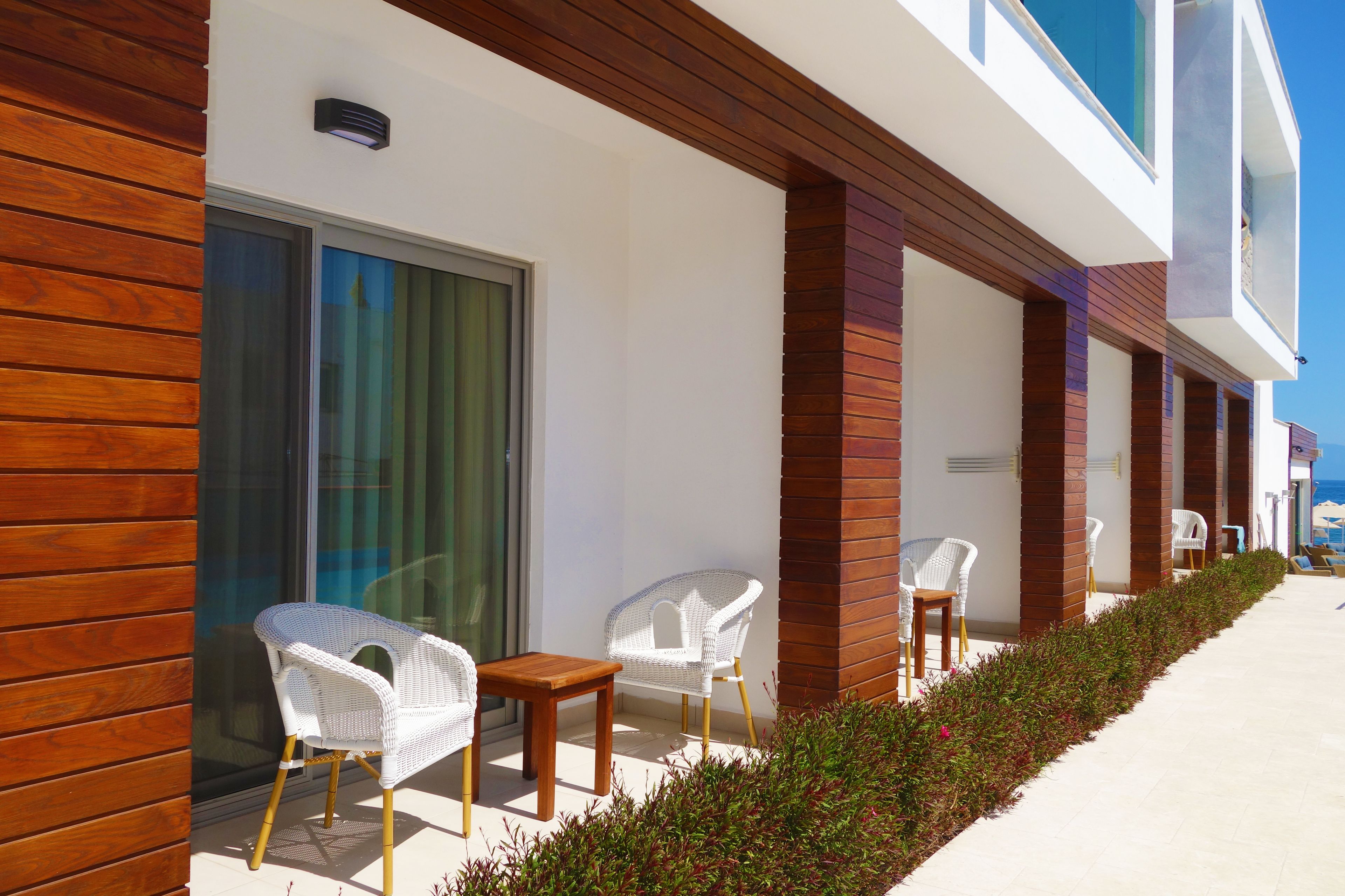 A modern building with a wooden facade, white wicker chairs, and a small table.