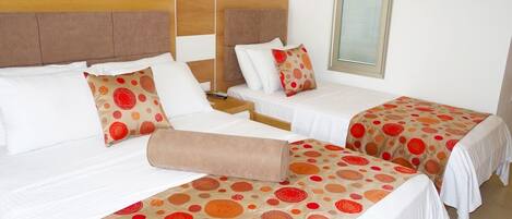 A hotel room with two beds, each with a patterned bedspread and matching pillows.