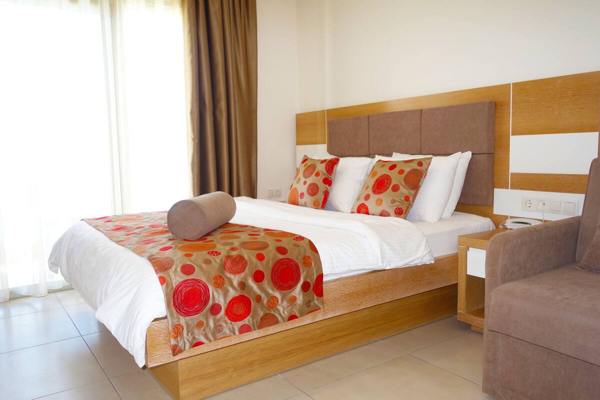 Una habitación de hotel con una cama de madera, ropa de cama blanca y un cabecero marrón.
