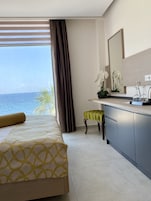A hotel room with a bed, a small stool, a sink, and a mirror.