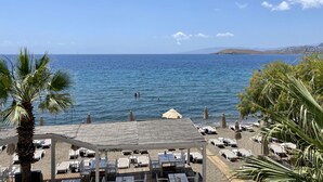 Une vue sur la plage, avec des chaises longues et des parasols, un ciel dégagé et une mer calme.