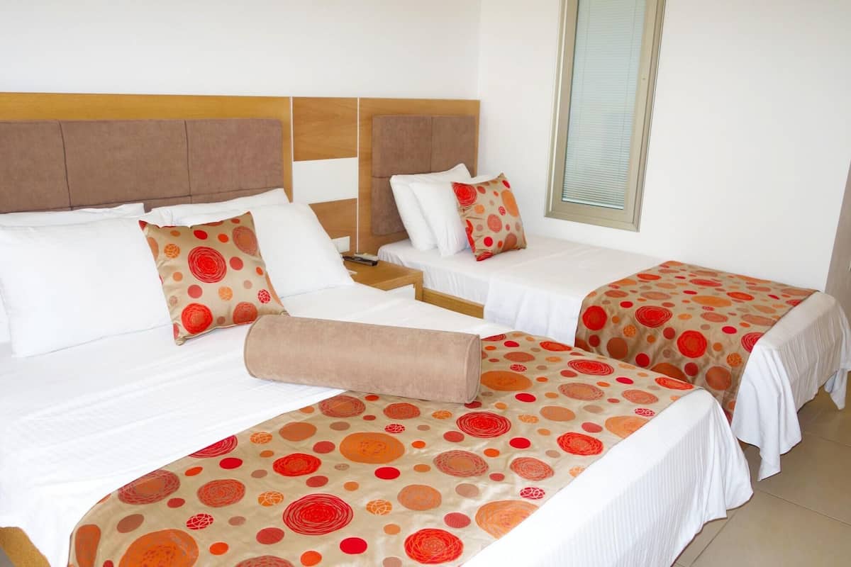 Habitación de hotel con dos camas, cada una con cabecera, ropa blanca y colcha estampada.