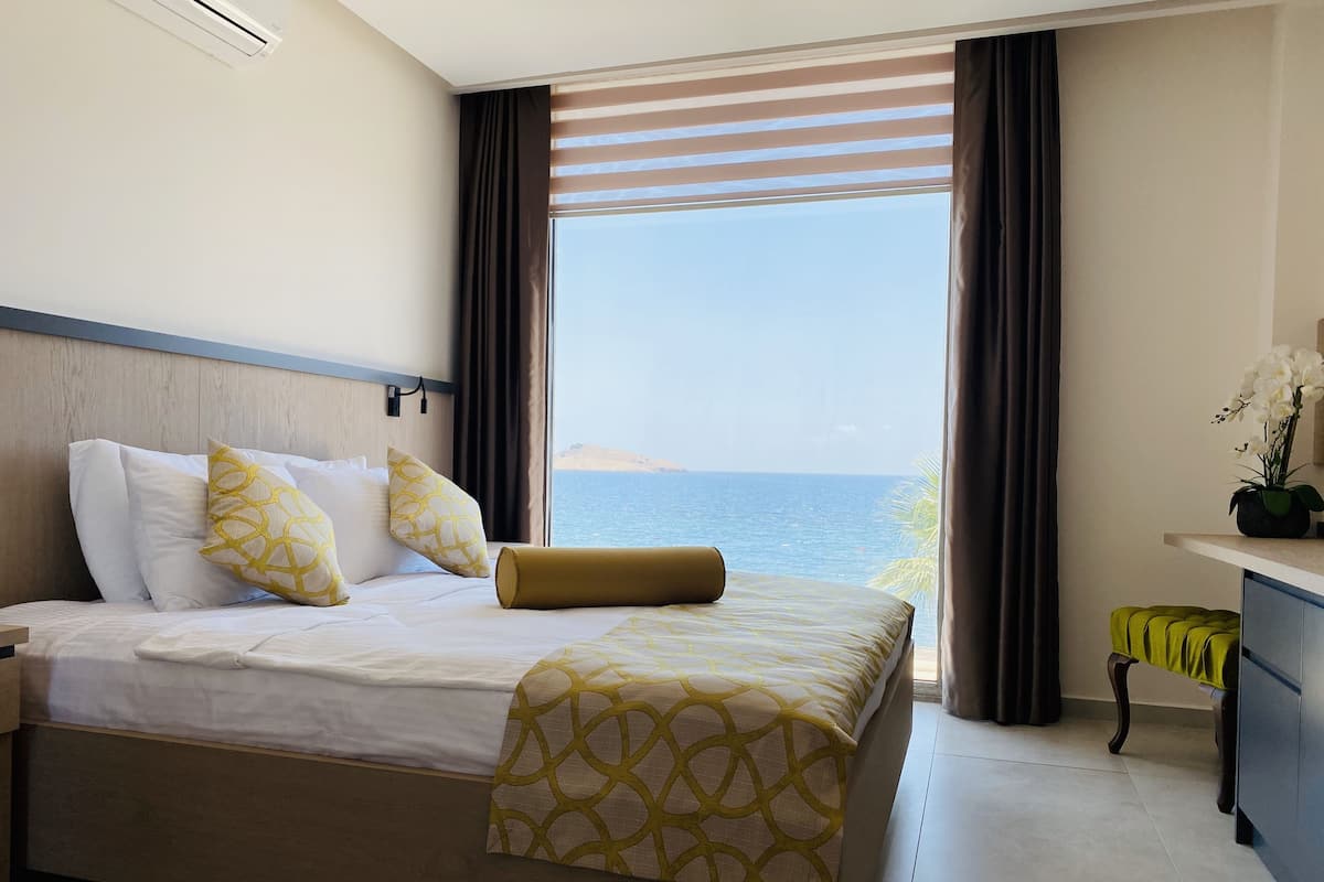 Una habitación de hotel con cama, mesita de noche, escritorio y vista al mar.