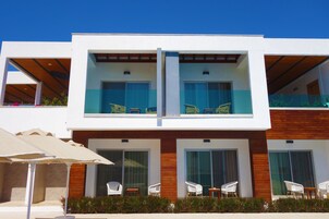 A modern two-story building with a balcony, large windows, and outdoor seating.