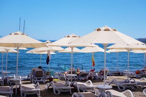 På stranden, liggestole, parasoller, badehåndklæder