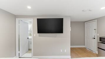 A bedroom with a bed, a TV mounted on the wall, and a door leading to a bathroom.