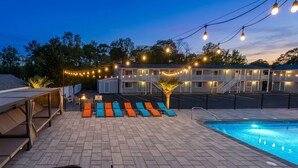 A pool area with lounge chairs, a hot tub, and string lights. - Dennis Port Surf Club (Boutique Hotel) (Dennis Port)