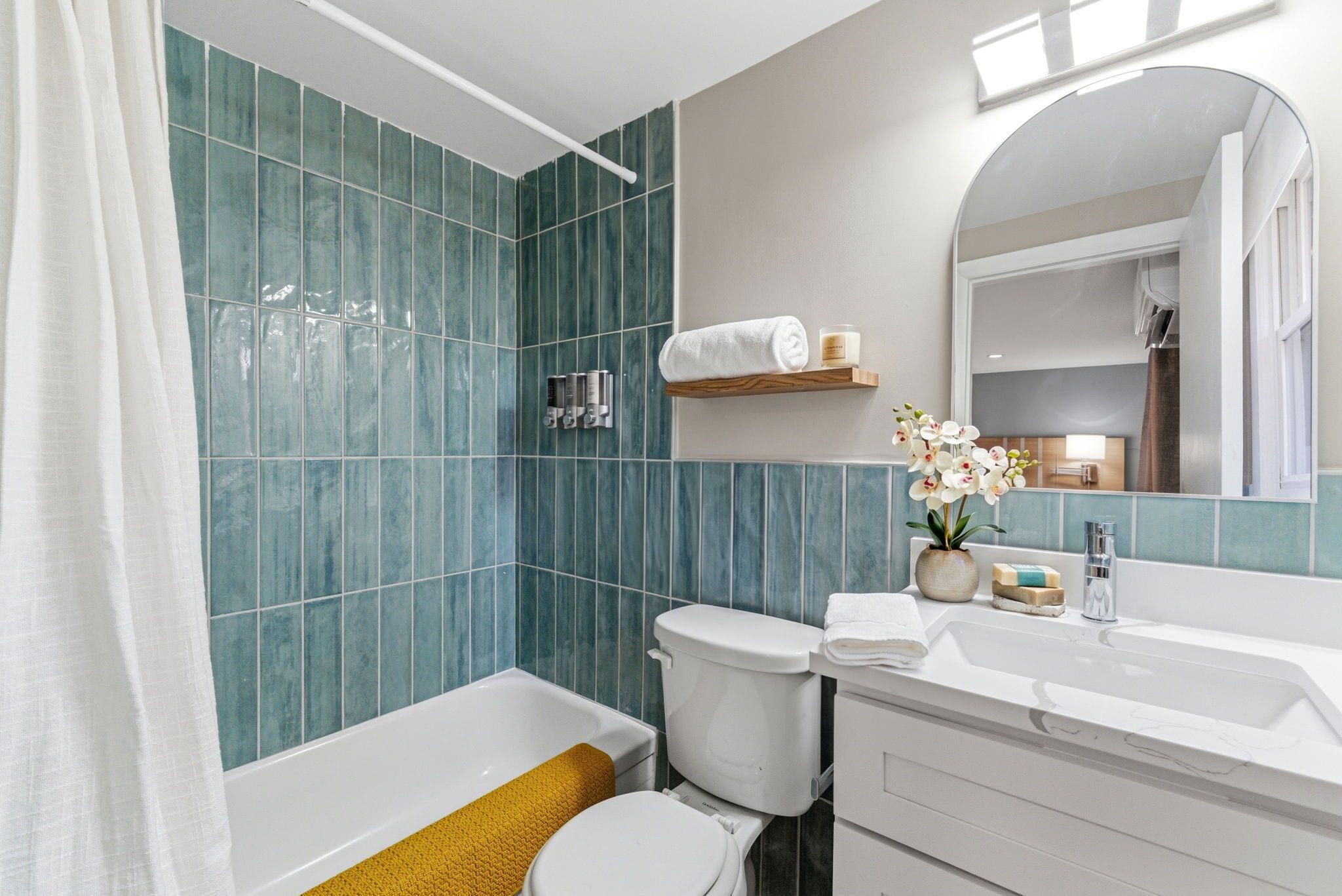 A bathroom with a bathtub, toilet, and sink, with a mirror above the sink.