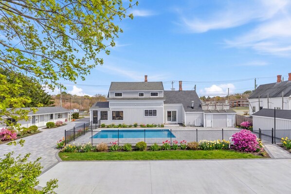 A residential area with a swimming pool, white houses, and a clear sky.