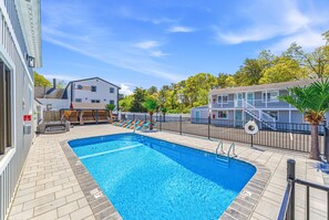 A swimming pool with a tiled deck, a lifeguard stand, and a fenced area with lounge chairs.