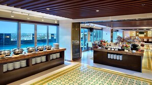A modern hotel lobby with a buffet area, large windows, and a patterned floor. - Aston Solo (Surakarta)