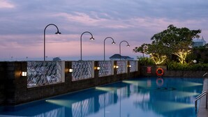 A swimming pool with a view of a building in the background, surrounded by a decorative fence with lights. - Aston Solo (Surakarta)