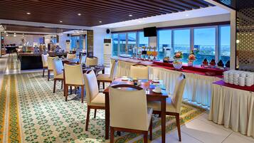 Un comedor de hotel moderno con una barra larga, varias mesas y sillas.