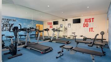 Un gimnasio con cintas de correr, bicicletas estáticas y máquinas de pesas.