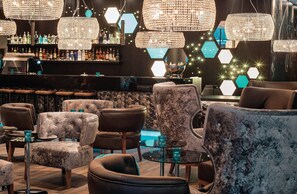 Zona de bar con diversas opciones de asientos, incluyendo sofás y sillones, y una barra con diferentes botellas.